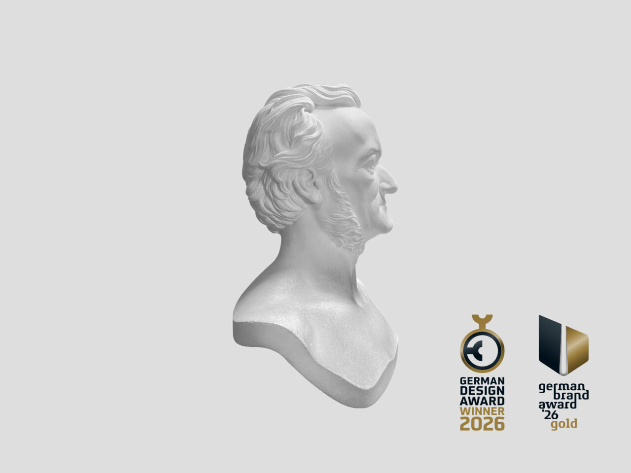 Corporate Design Case: Ausstellung Mensch Wagner 2024. Das Bild zeigt eine weiße Büste von Richard Wagner im Profil auf grauem Hintergrund. Die Büste bildet das zentrale Motiv des Designkonzepts. Rechts darunter ist das Gewinner Logo des German Design Awards 2026 abgebildet.